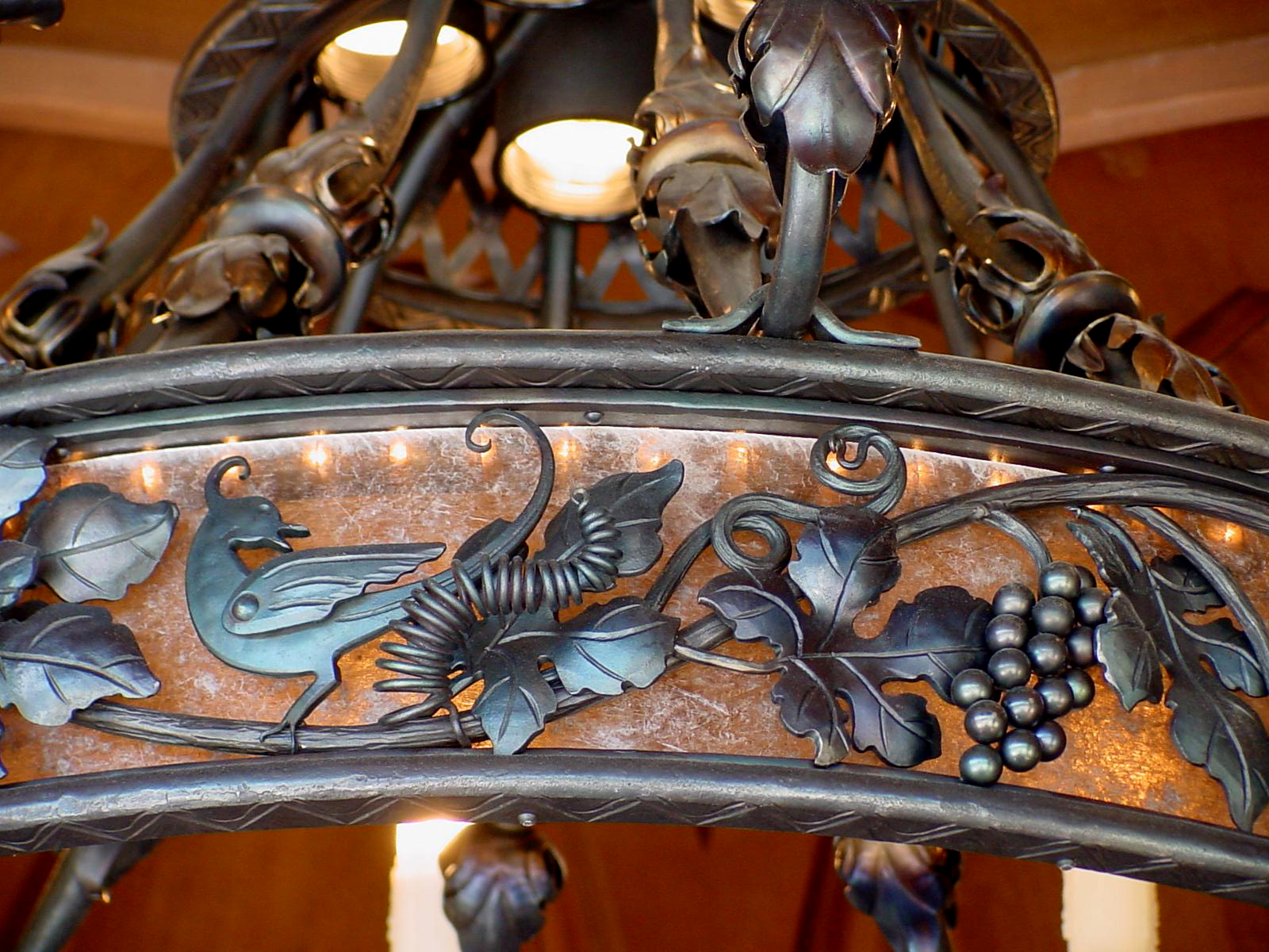 Detail shot of the hand forged Dining Room Fixture with sheet mica fill behind the bird grape detail Design by Morrelli